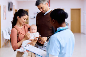 Parents with baby daughter talking to a family nurse practitioner in hallway of a medical clinic